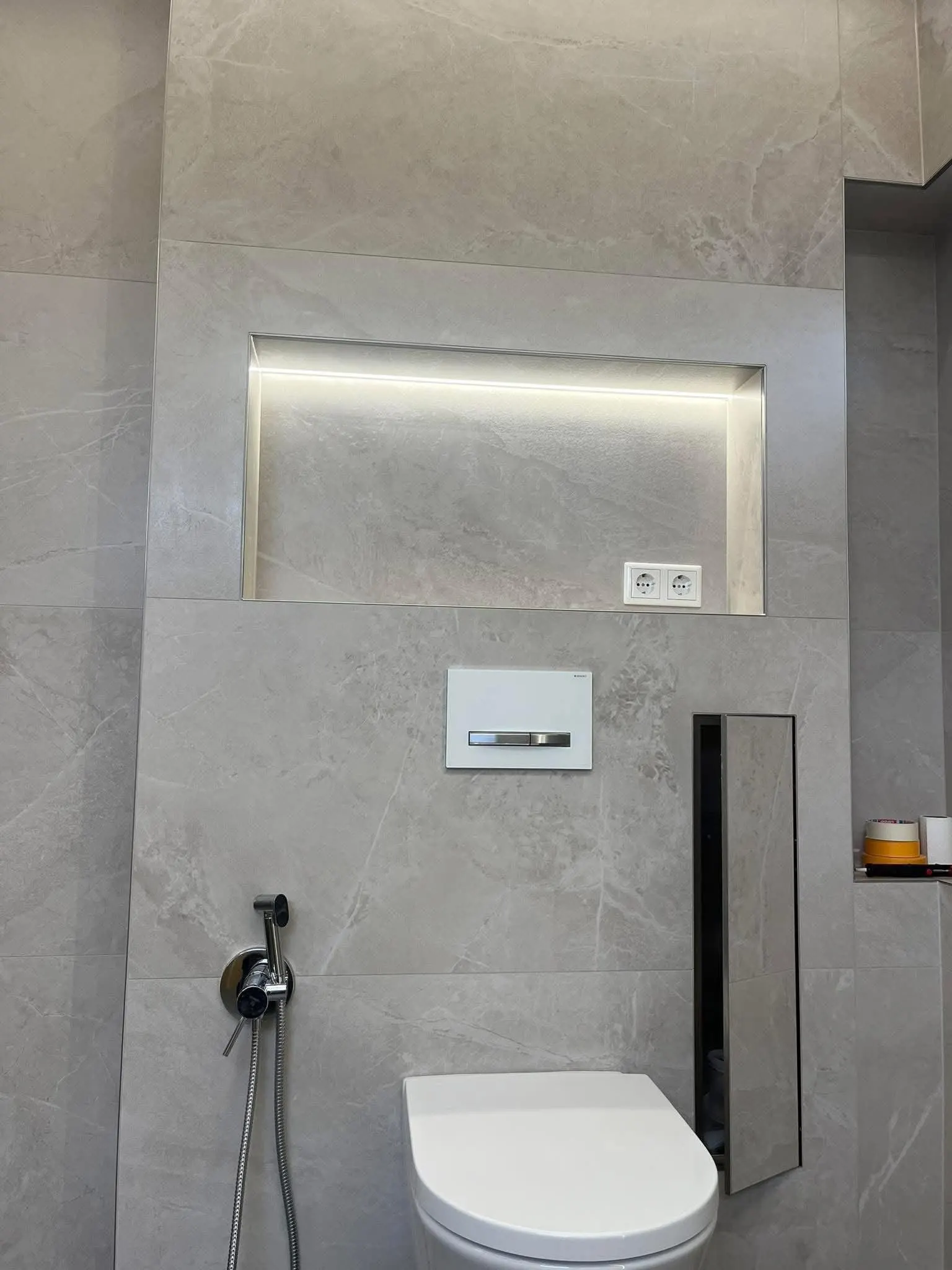 Gefliestes Bad in Steinoptik mit beleuchteter Wandnische und wandhängendem WC